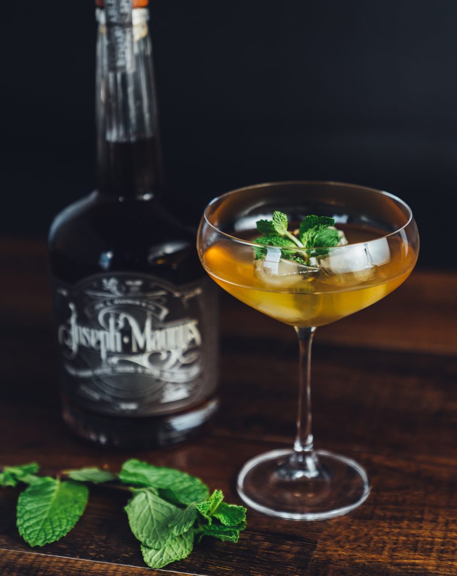 A Bourbon Smash beside a bottle of Joseph Magnus